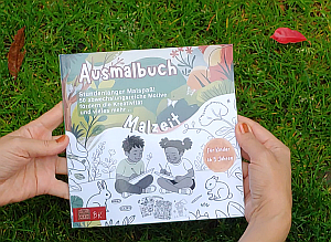 Buch Cover: Zwei Kinder mit Malblöcken sitzen in der Natur, umgeben von Hasen, Blumen und Schmetterlingen – obere Hälfte farbig, untere schwarz-weiß. Malbuch Mira Sonnentrail